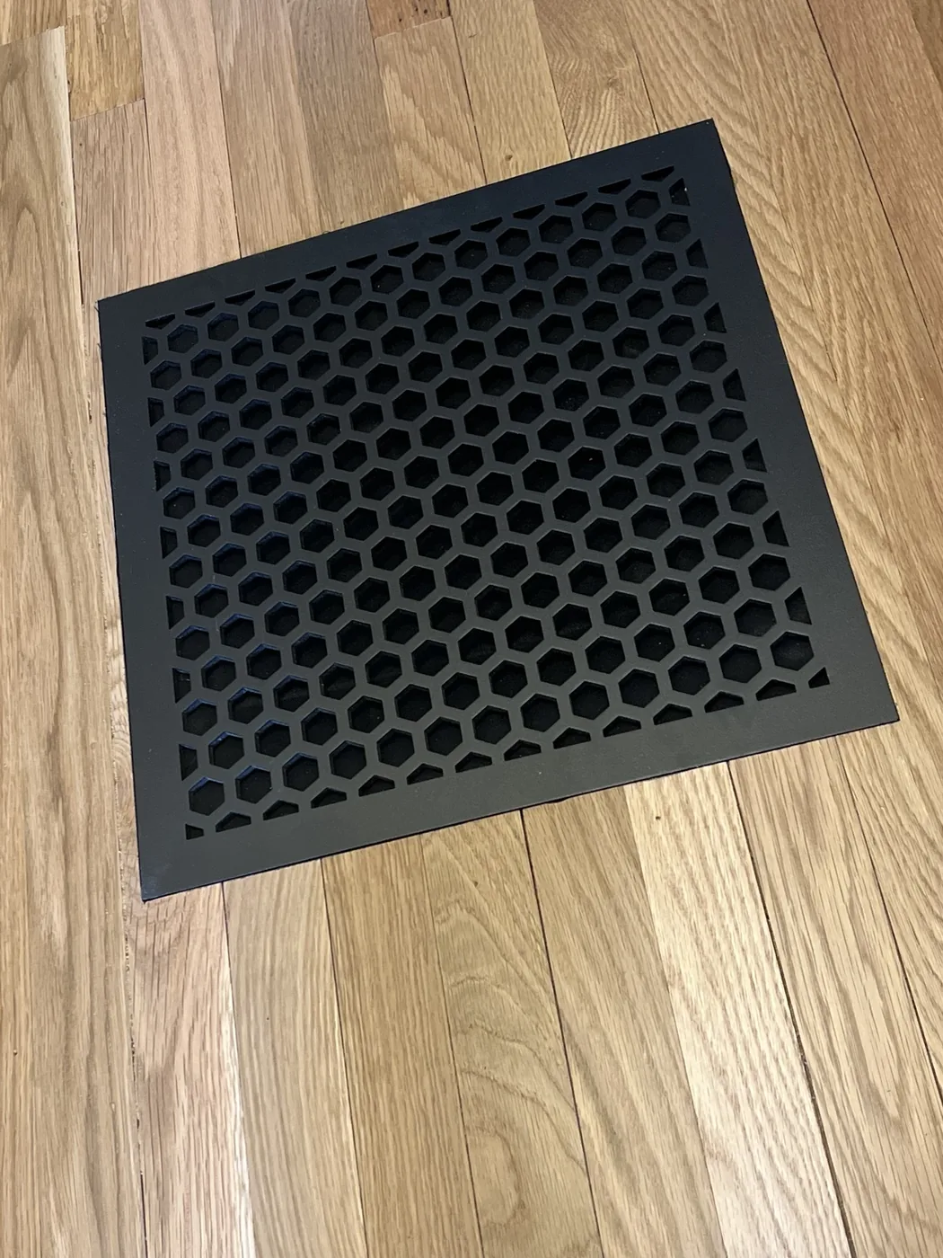 Flush mount black vent installed in existing oak flooring